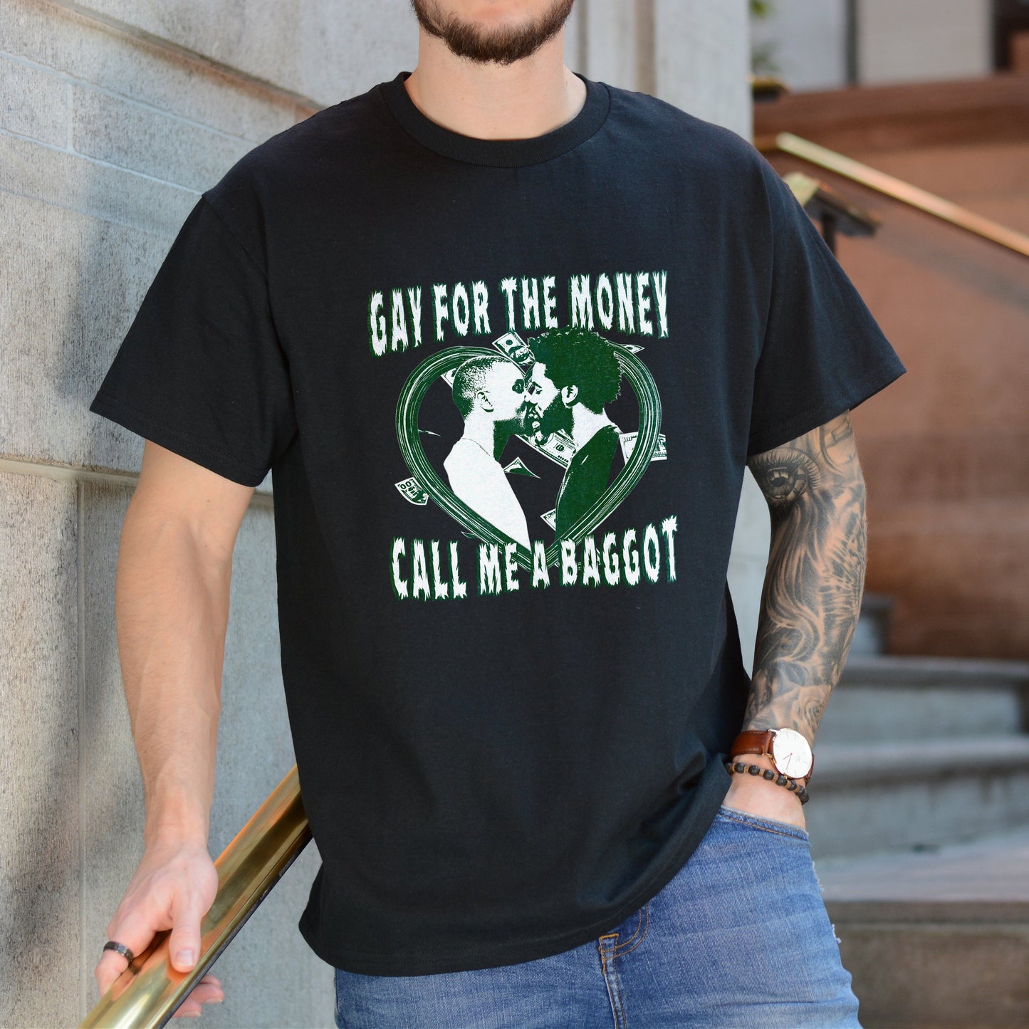 Person wearing a black t-shirt with graphic design and text, standing against a building.