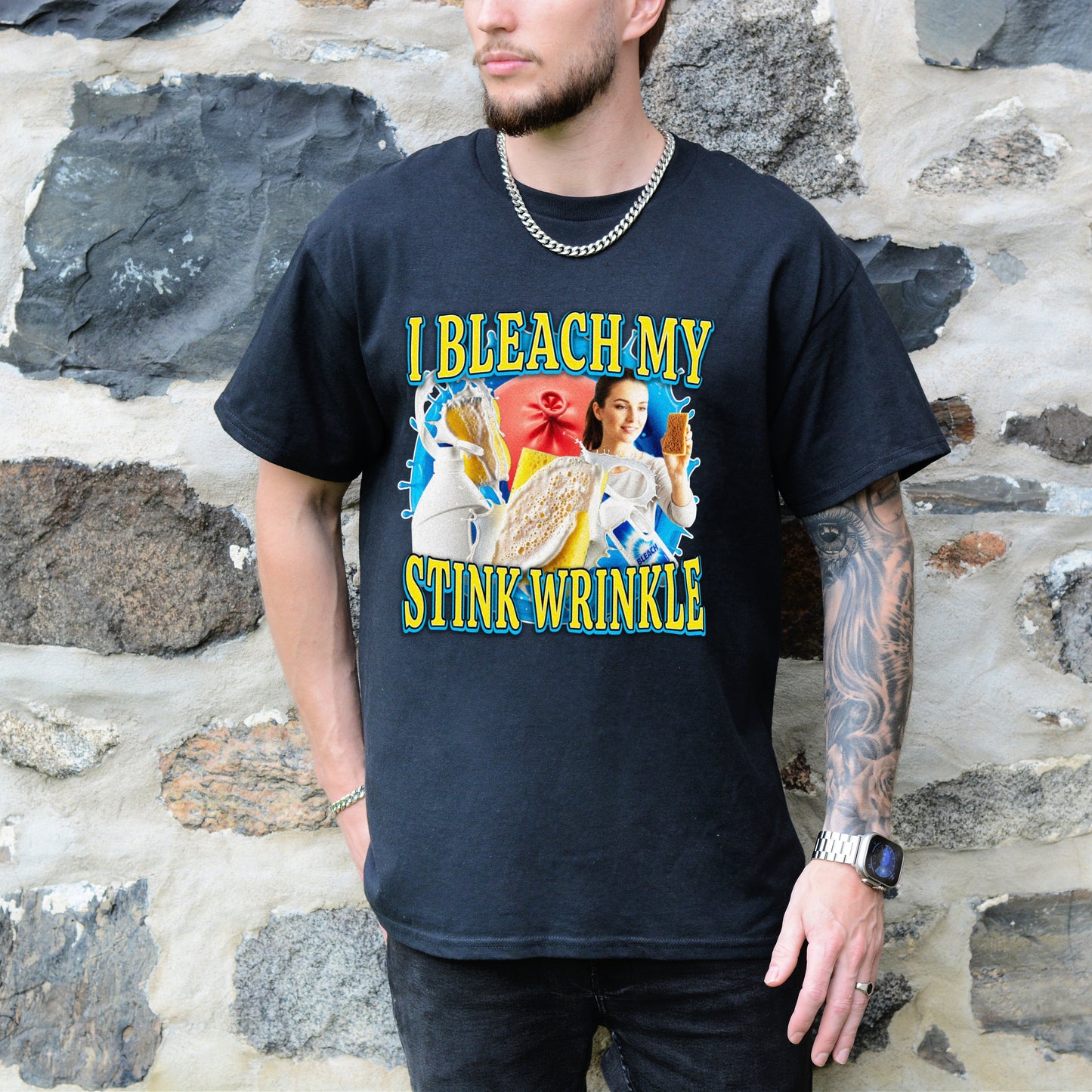 Person wearing a black t-shirt with colorful graphic design and text against a stone wall background