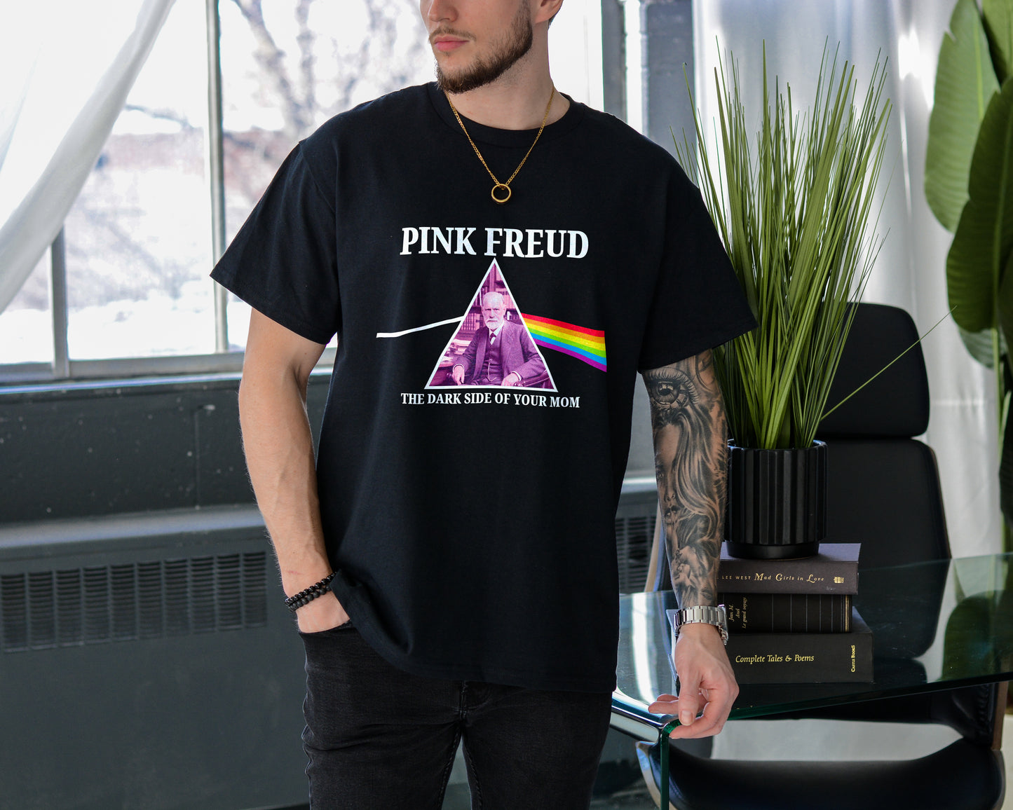 Person wearing a black t-shirt with 'Pink Freud' graphic design indoors.