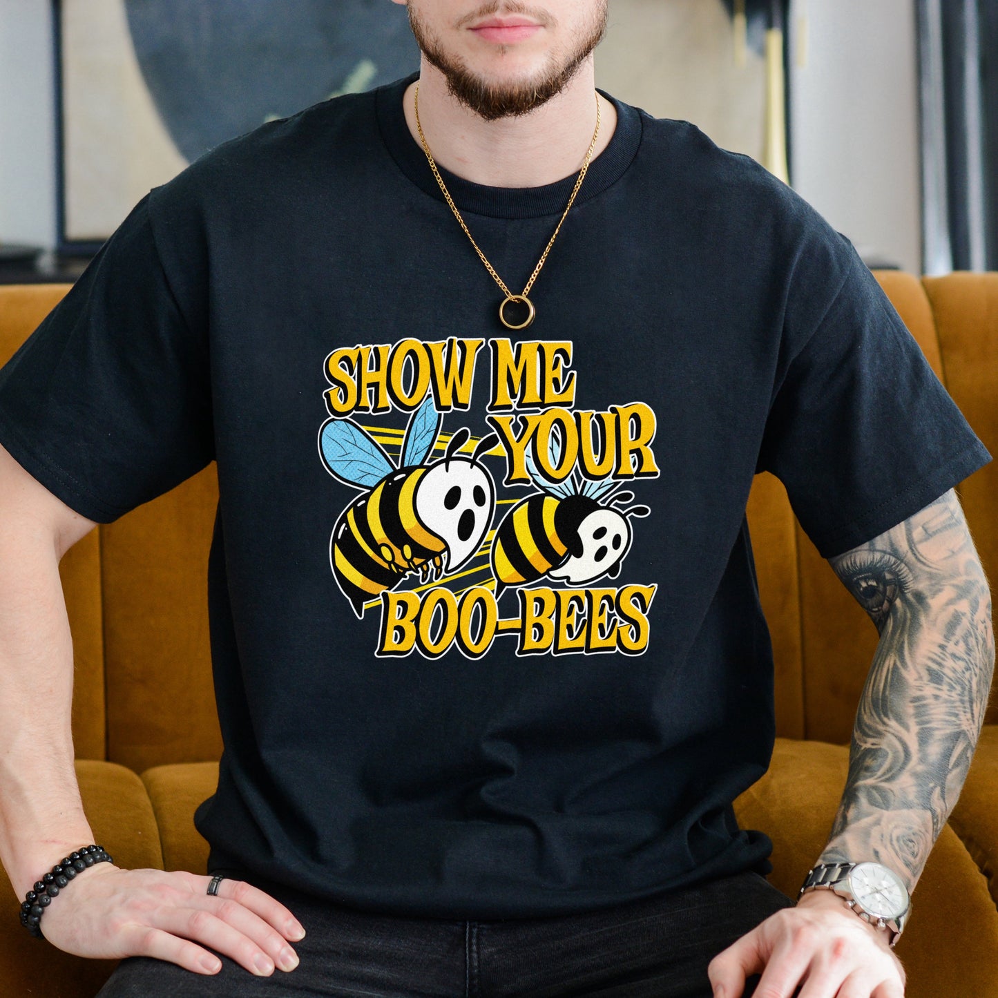 Person wearing a black t-shirt with a graphic design and text, sitting on a mustard yellow couch.