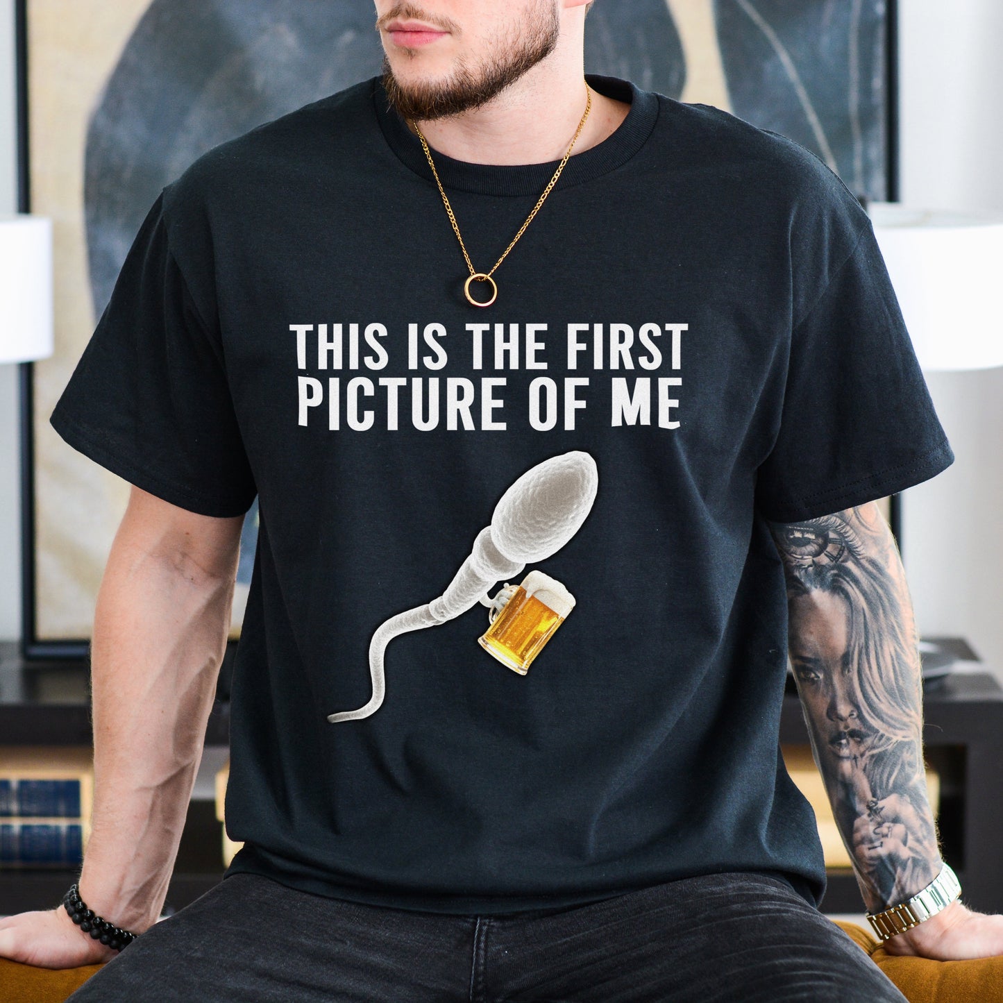 Person wearing a black t-shirt with a graphic and text in a room.