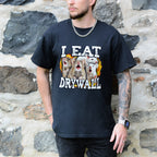 Person wearing a black t-shirt with a graphic design and text, standing against a stone wall.