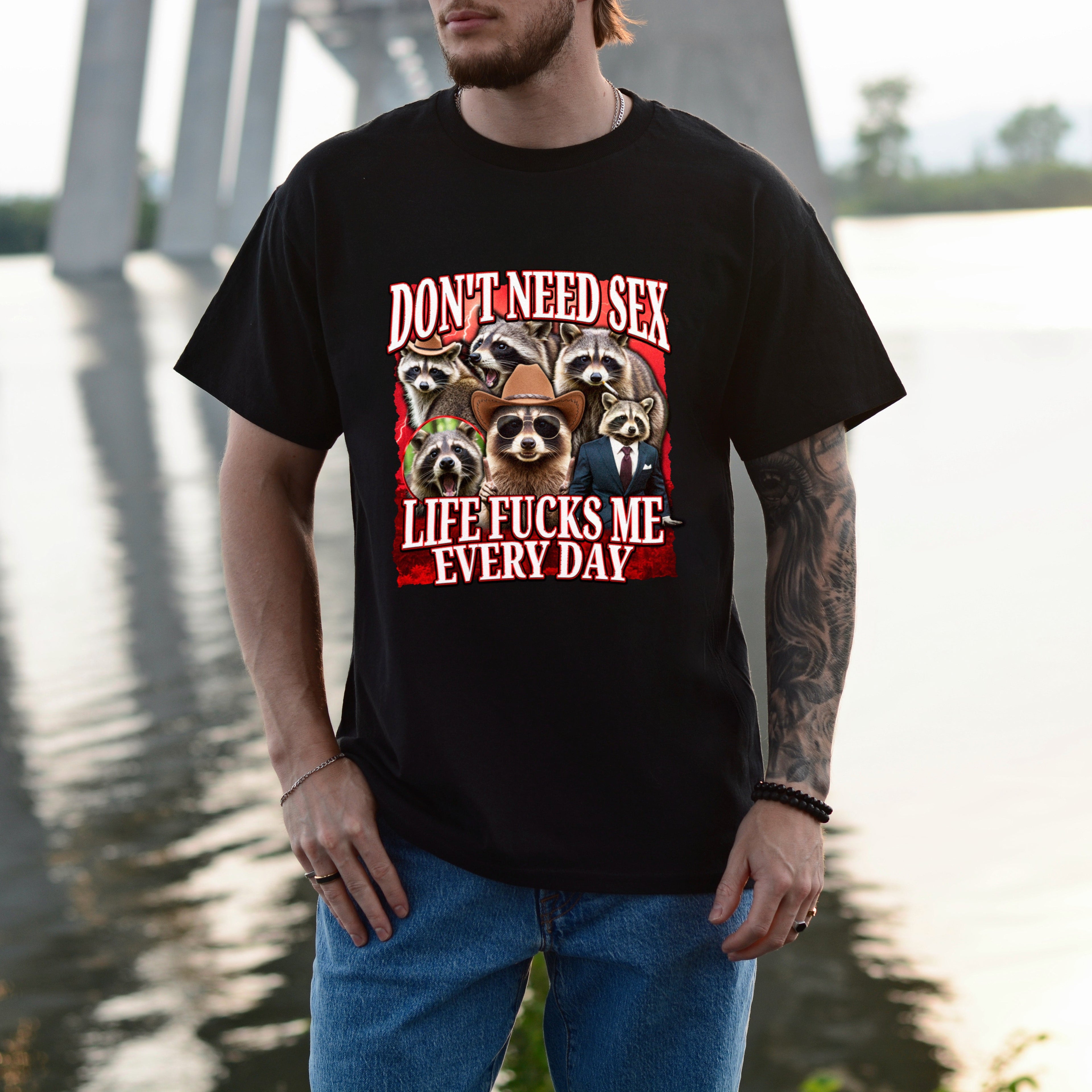 Person wearing a black t-shirt with graphic design and text by a body of water.