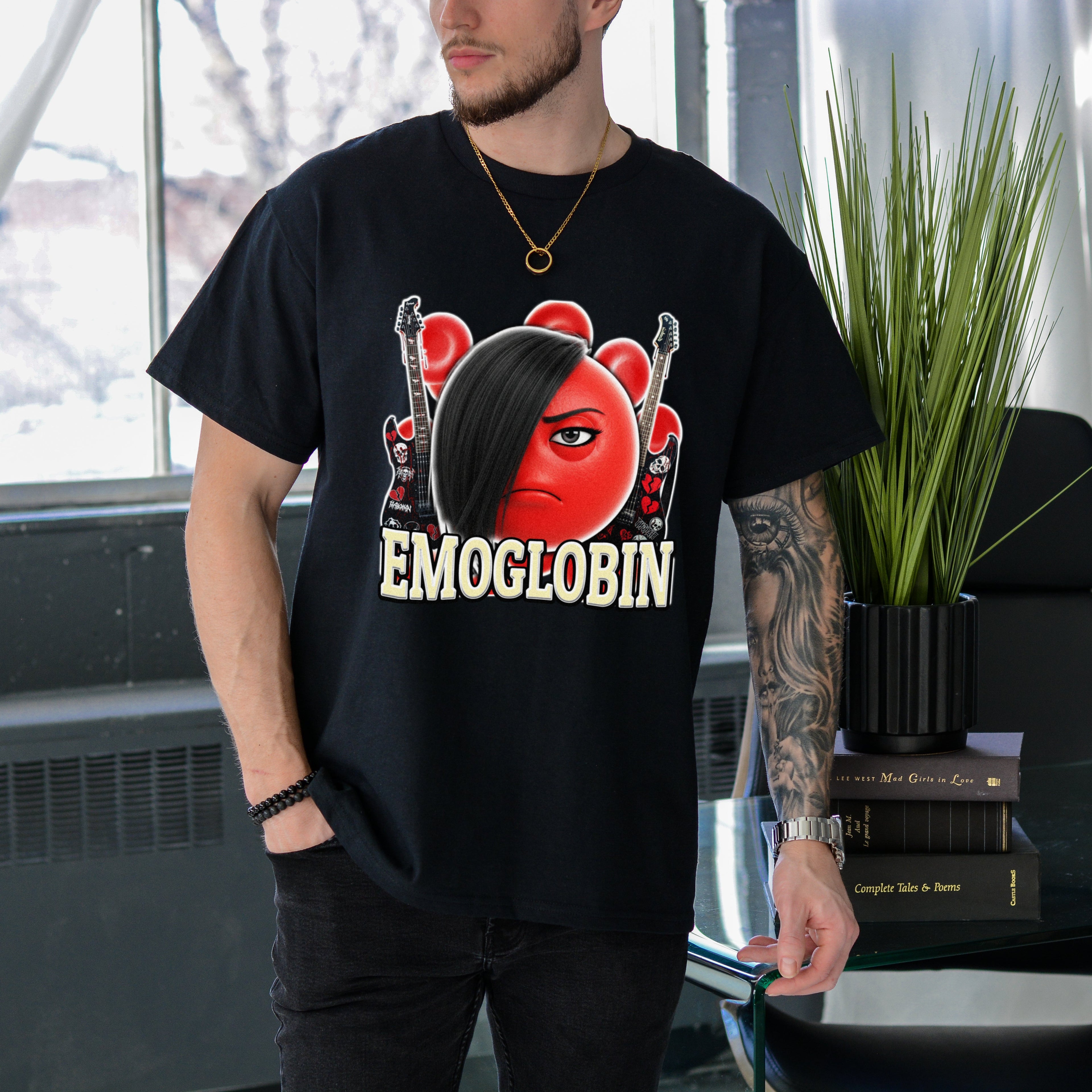 Person wearing a black t-shirt with a graphic design and text, standing indoors.