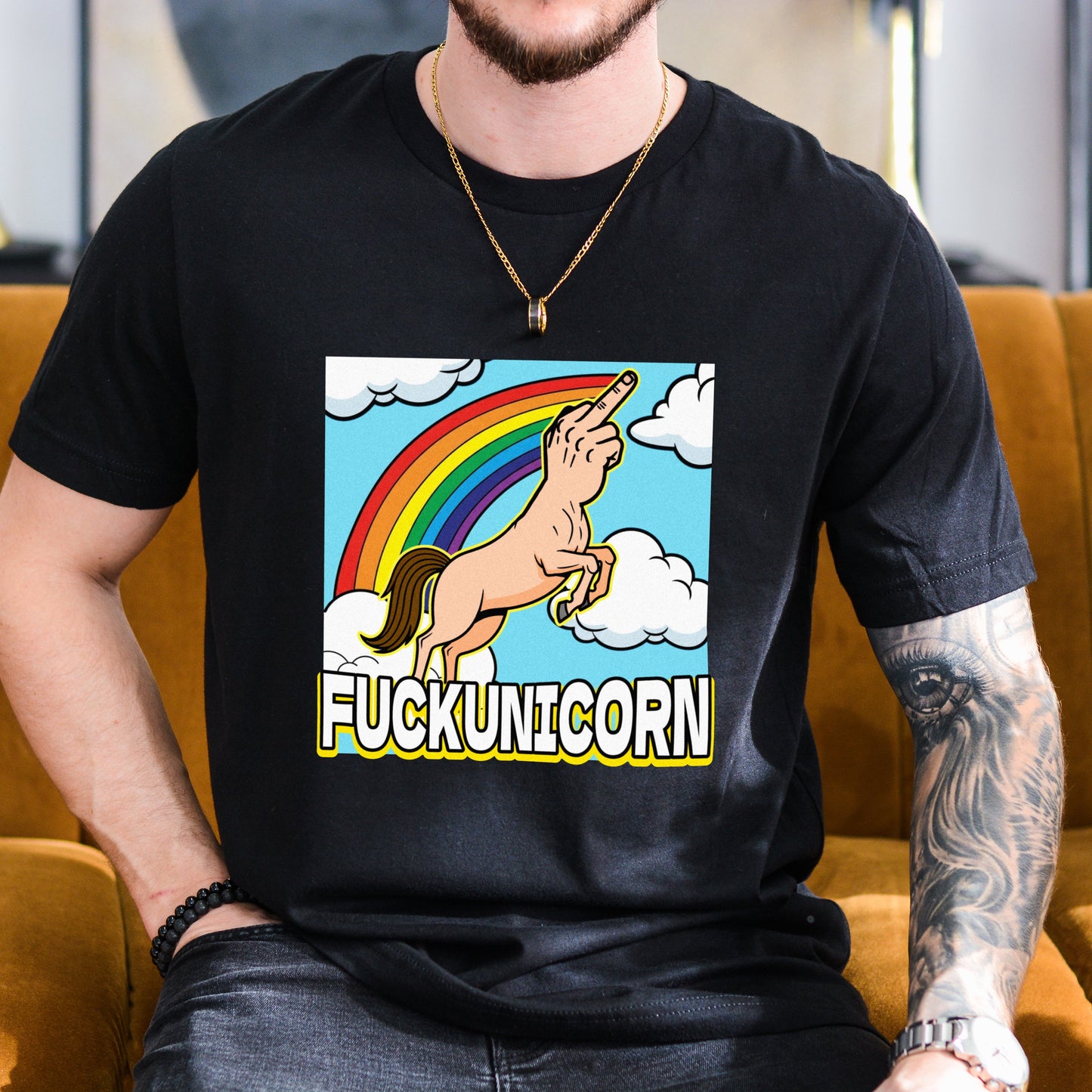 Person wearing a black t-shirt with a colorful graphic and text, sitting on a brown couch.