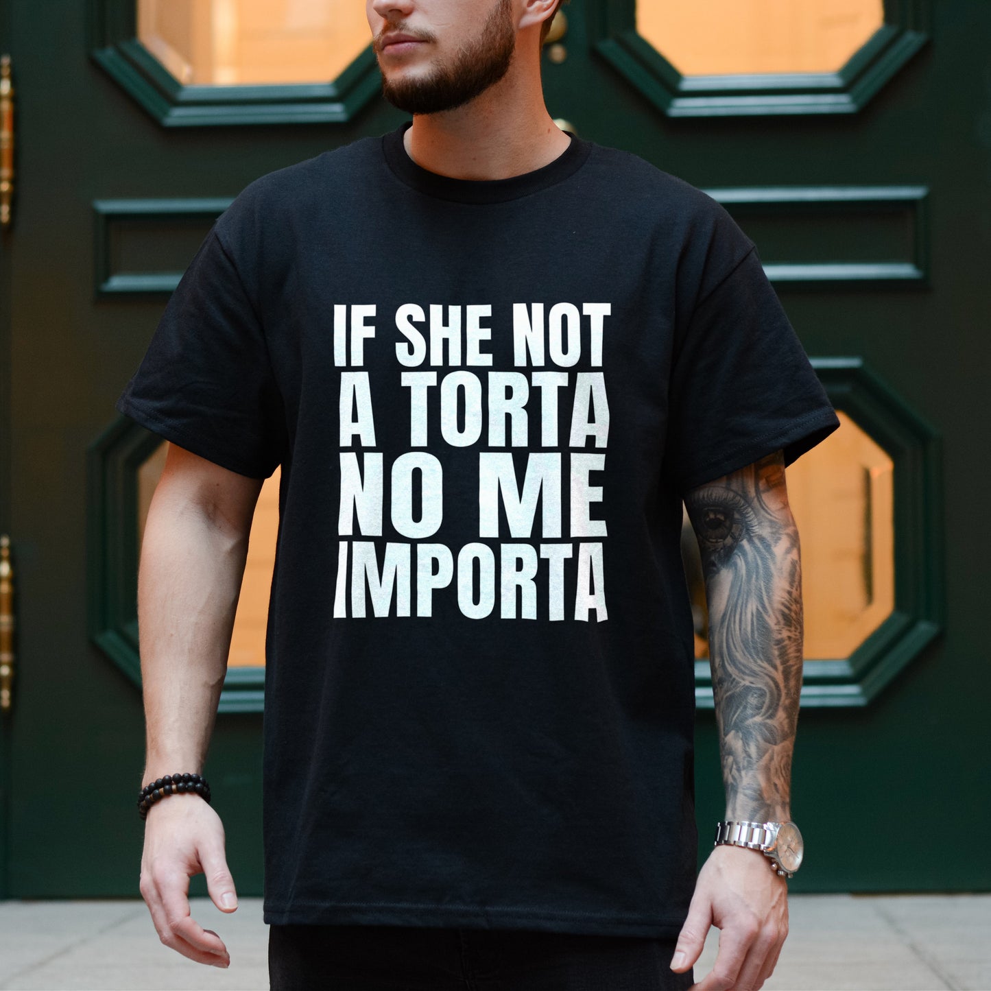 Person wearing a black t-shirt with white text in front of a green door.