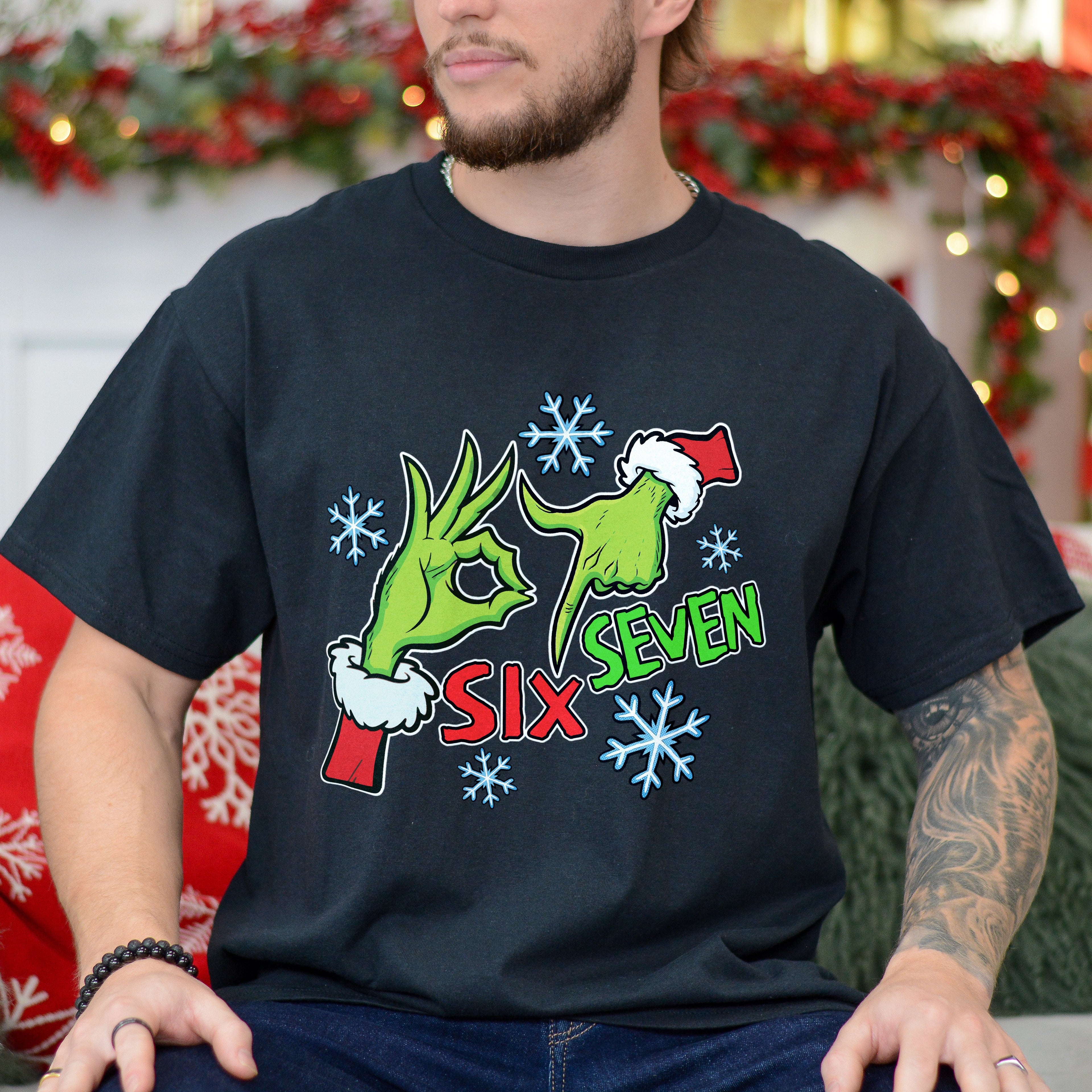 Person wearing a black t-shirt with a festive design in a decorated room.