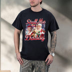 Person wearing a black t-shirt with a graphic design and text, standing against a neutral wall.