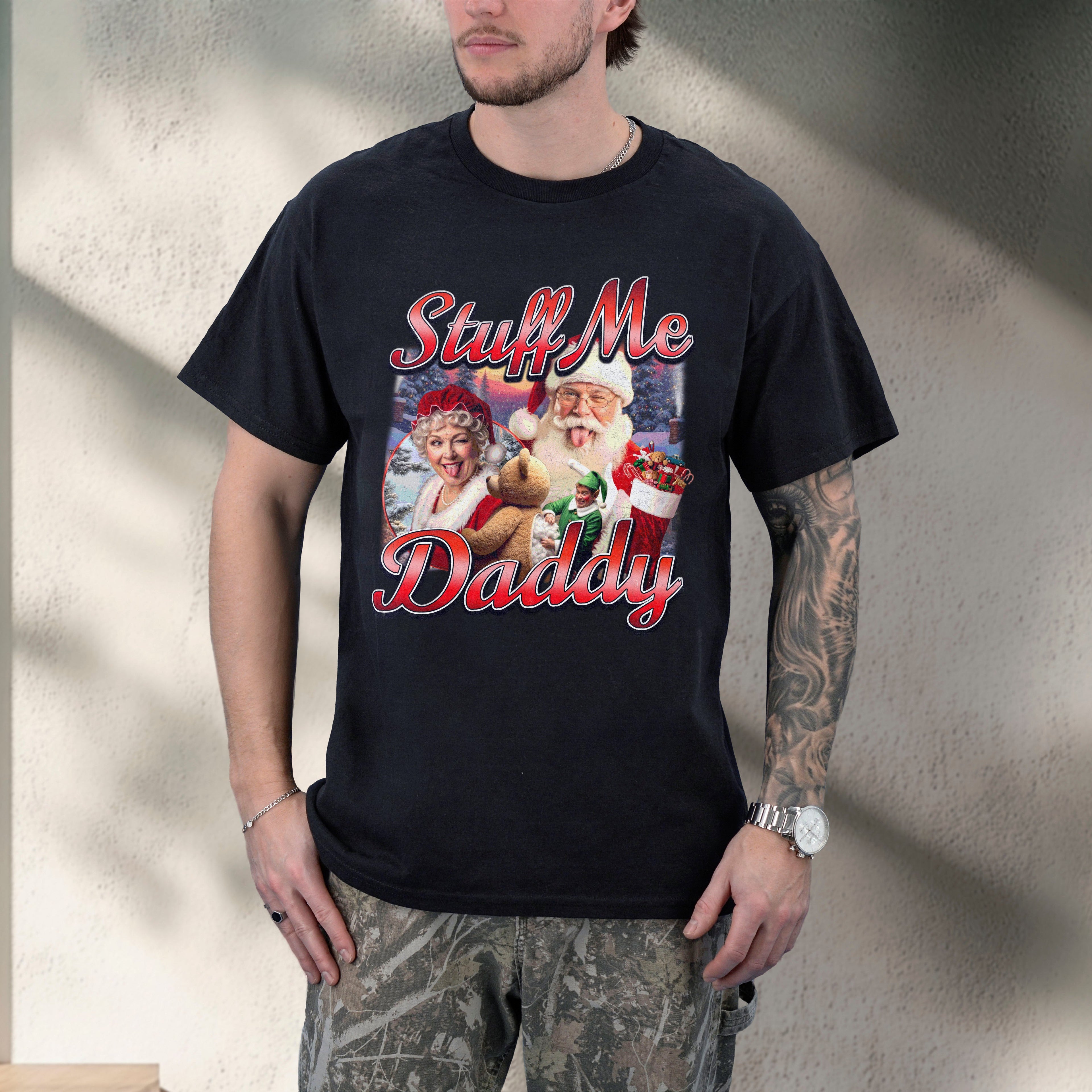 Person wearing a black t-shirt with a graphic design and text, standing against a neutral wall.