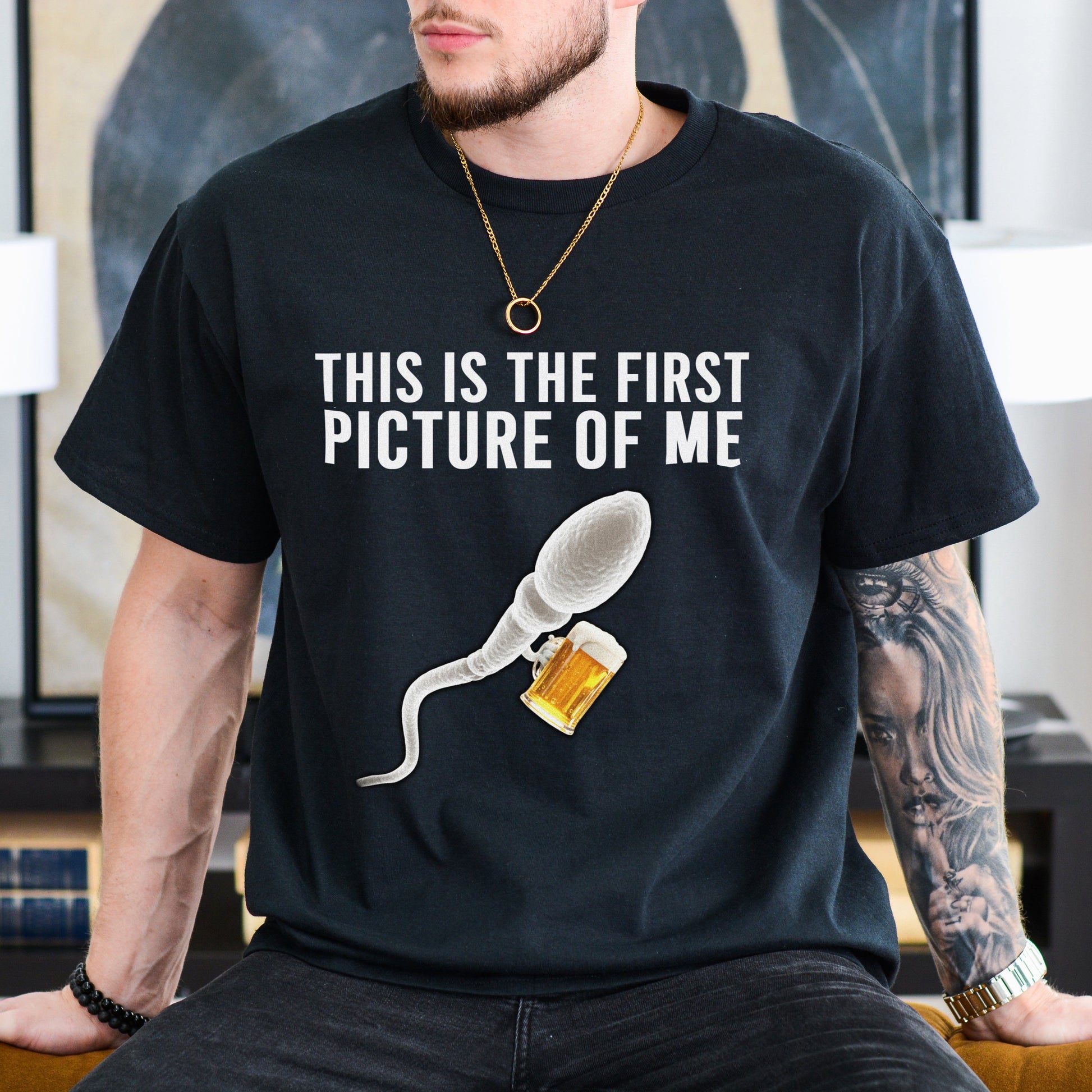 Person wearing a black t-shirt with a graphic and text in a room.