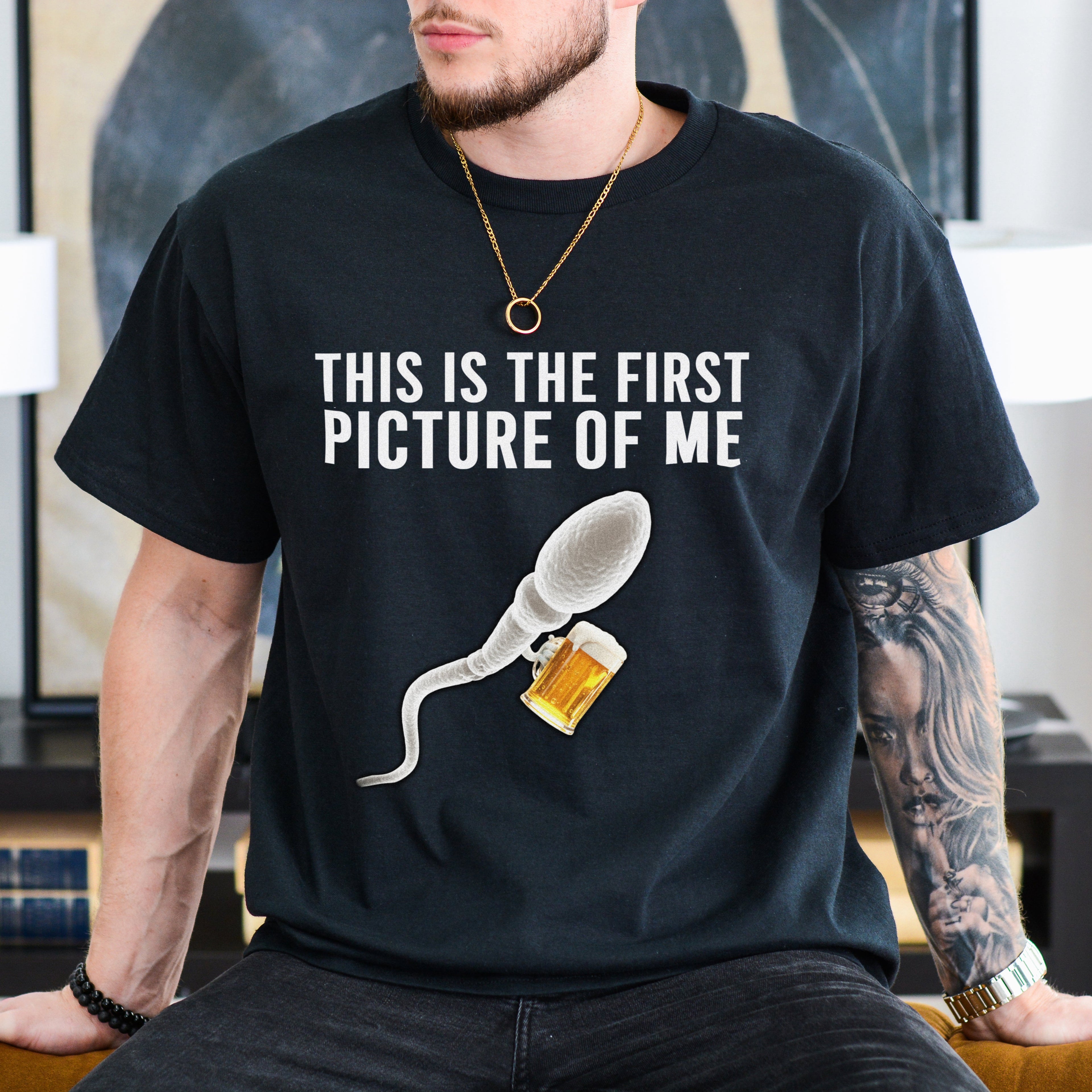 Person wearing a black t-shirt with a graphic and text in a room.